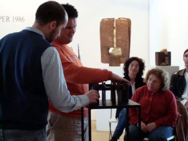 Una trentena de persones miren amb les mans les obres d’Elisa Arimany